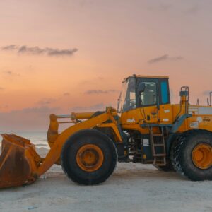 A bulldozer at a beach construction site during sunset, showcasing coastal development.